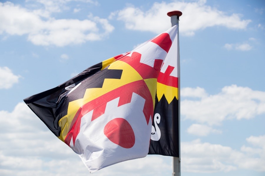 wapperende vlag met gemeentewapen in de kleuren rood, geel, zwart en wit